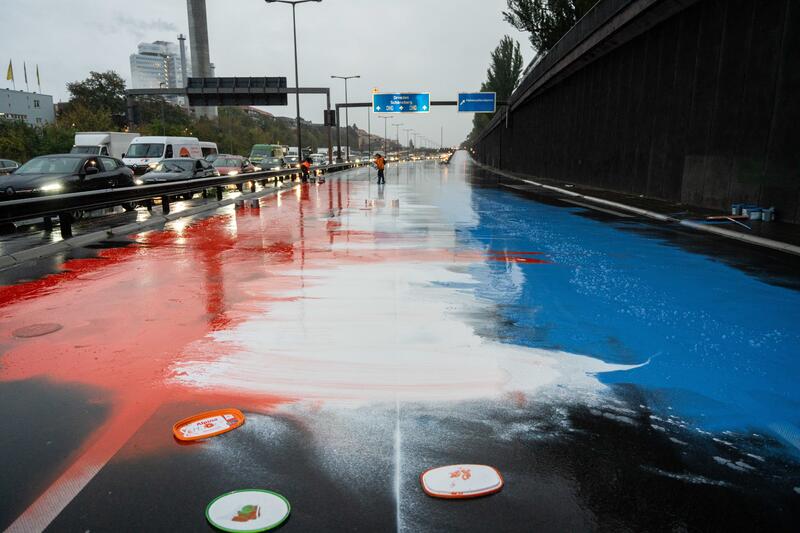 Erneut haben Aktivist*innen der Letzten Generation am 12.10.2023 die A100 blockiert. Sie bremsten den Verkehr ab und blockierten mit Mietwägen und Ankleben den Verkehr. Außerdem warfen sie Farbe in den Nationalfarben der Niederlande auf den Boden. Dort blockierten täglich und über Wochen tausende Menschen die A12 in Den Haag mit der Forderung an die Regierung, fossile Subventionen zu beenden. Am Dienstag beendete das niederländische Parlament die Subventionen für fossile Brennstoffe.   --   Once again activists of the Last Generation blocked the A100 on October 12, 2023. They slowed down the traffic and blocked the traffic with rental cars and stickers. They also threw paint in the national colors of the Netherlands on the ground. There, thousands of people blocked the A12 in The Hague every day for weeks, demanding that the government end fossil fuel subsidies. On Tuesday, the Dutch parliament ended fossil fuel subsidies.