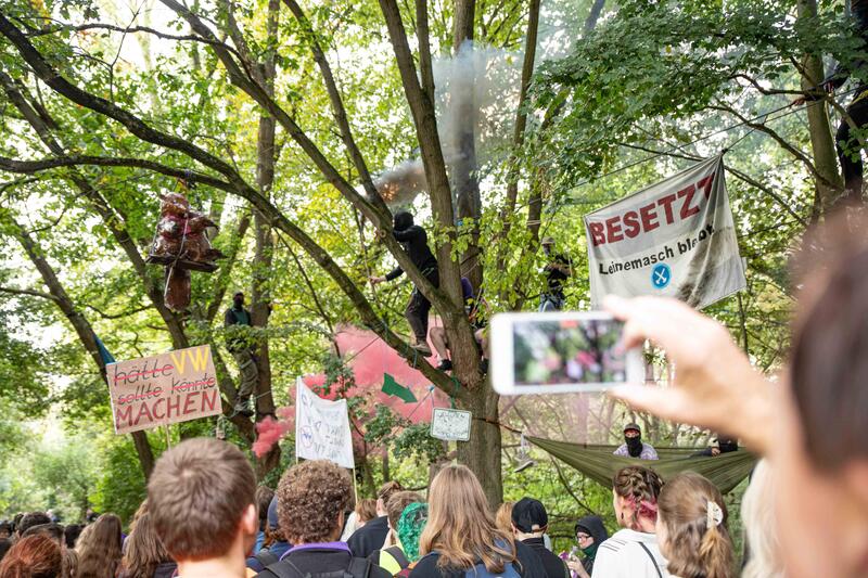 Baumbesetzer zünden Pyro. Am 01.10.2023 protestieren Tausende mit einer Demonstration für den Erhalt des Leinemasch, ein Waldstück, von dem 13 Hektar für den Ausbau des Südschnellwegs gerodet werden sollen. Am Rande besetzten Aktivist*innen von Ende Gelände die Baustelle der Bundesstraße. Seit einem Jahr ist dieses von Aktivist*innen besetzt, die sich mit Baumhäusern der Rodung entgegenstellen.  - Occupiers use bengal fires. On 01.10.2023 thousands protest for the preservation of the Leinemasch forest. A piece of forest from which 13 hectares are to be cleared for the expansion of the Südschnellweg. On the edge activists from Ende Gelaende occupied the construction site of the federal highway. For a year now, it has been occupied by activists who oppose the clearing with tree houses.