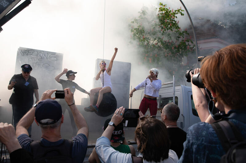 Die selbsternannten "Spezial-Enteignungskräften (SEK) reißen in einem symbolischen Akt die Mauer zwischen Arm und Reich mit einer Abrissbirne aus Pappmasche ein. Unter dem Thema "Razzia im Villenviertel" veranstaltet das Bündnis "my Gruni" am 01.05.2024 einen satirischen Demonstrationszug durch Berlin Grunewald. Etwa 4000 Menschen schließen sich dem Protest an. In verschiedenen Aktionen stellen die Veranstalter*innen eine Razzia gegen Steuervergehen nach. Hiermit prangern sie soziale Ungleichheiten an und üben Kritik an der lockeren Verfolgung von Kapitalverbrechen. - In a symbolic act, the self-proclaimed "special expropriation forces" (SEK) tear down the wall between rich and poor with a cardboard wicker bulb. Under the theme "Razzia im Villenviertel", the alliance "my Gruni" organizes a satirical demonstration march through Berlin Grunewald on 01.05.2024. About 4,000 people joined the protest. In various actions, the organizers recreate a raid against tax offences. In doing so, they denounce social inequalities and criticise the lax prosecution of capital crimes.