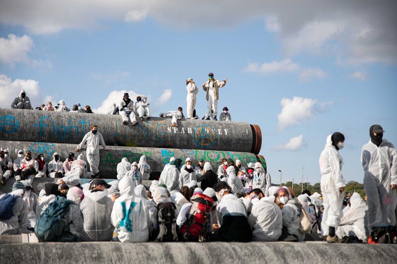 Etwa 900 Aktivist*innen demonstrierten 23.9.2023 im Rahmen eines Aktionswochenendes des Bündnis Ende Gelände auf Rügen. Sie kritisieren die Darstellung von LNG als saubere Brückentechnologie. Zwei Finger sind aus der Demo ausgebrochen und besetzen das Hafengelände von Mukran. --   Around 900 activists demonstrated September 23, 2023 as part of an action weekend of the Ende Gelaende alliance on Ruegen, Germany.  They criticized the presentation of LNG as a clean and eco-friendly bridging technology. Two fingers broke through the police chain and occupied the Mukran Port.