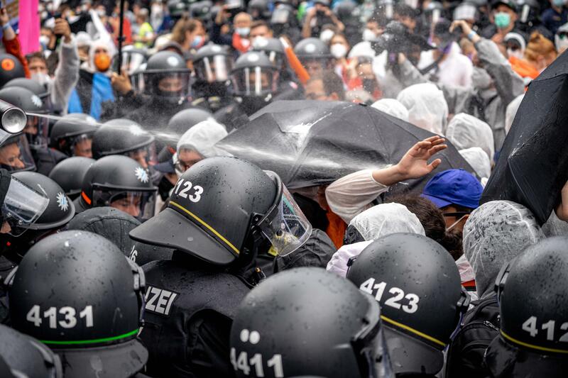Polizist sprüht mit Pfefferspray in die Menge. Am 11. September 2021 versammelten sich in München 25.000 Menschen, um für eine Mobilitätswende und gegen die IAA Mobility zu demonstrieren. Als Aktivit*innen auf Bäume stiegen, kam es zu einem massiven Einschreiten der Polizei, die teilweise extrem brutal auf Journalist*innen vorging. Alto Press Fotograf Aaron Karasek musste die Berichterstattung vorzeitig abbrechen und war durch den mutmaßlich gezielten Angriff durch einen bayerischen Polizisten mehr als 24 Stunden arbeitsunfähig.   *   Police officer uses pepper spray. On September 11, 2021 25.000 people joined a demonstration against the IAA Mobility and for a mobility turnaround. When activists climbed onto trees, the police massively intervened. Journalists were targeted attacked by police officers. Alto Press photographer Aaron Karasek had to interrupt the coverage of the protest after a police officer made a presumed targeted attack with pepper spray on him. He couldn't work for more than 24h.