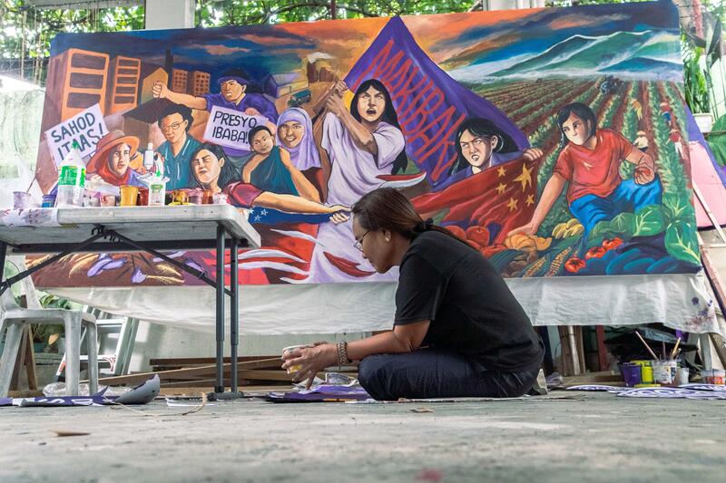 Jocelyn Bartolome, 58, a member of Artista ng Bayan (People’s Artist), prepares handwritten placards on March 7, 2025, in Quezon City, Philippines, for International Women’s Day. The placards feature a call in Filipino that translates to “Enough with violence against women!”