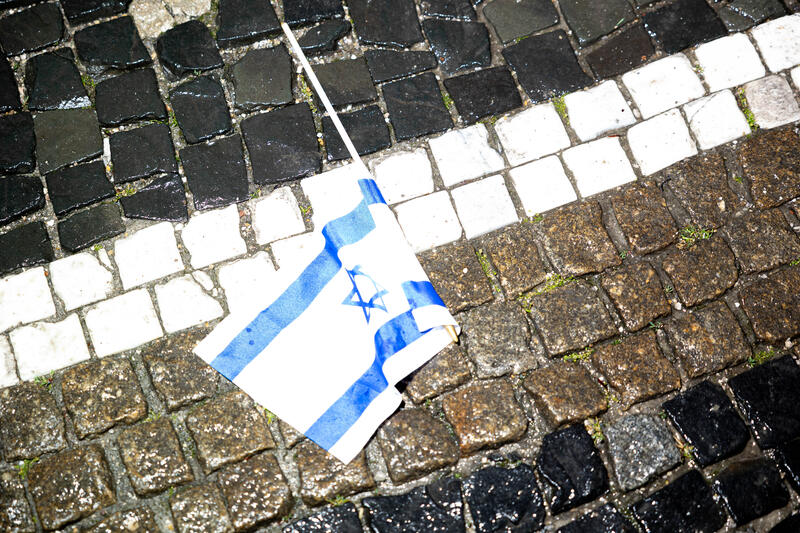 Der Wind wehte die Flagge auf den Boden. Zahlreiche Stände wurden zum Israeltag am 22.05.2025 am Odeonsplatz in München aufgestellt. Auf der Bühne wurde hauptsächlich gesungen. Etwa zwei bis drei Dutzend Zuschauer stellten sich bei Regen unter die Schirme.   --   The wind has blown the flag to the ground. Numerous stands were set up for Israel Day on May 22, 2025 at Odeonsplatz in Munich, Germany. Around two to three dozen spectators stood under the umbrellas in the rain.