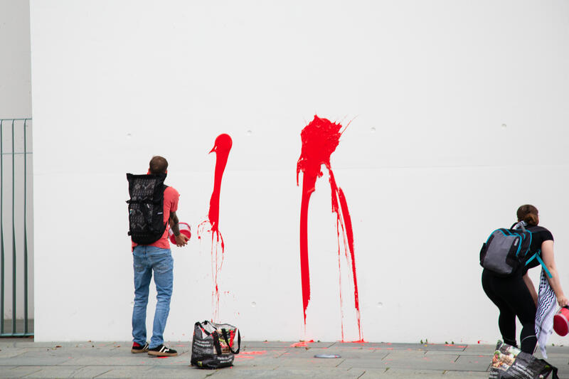 Am 07.07.2025 um 12 Uhr beschmierten Aktivist*innen von Palestine Rising die rechte Seite der Fassade des Bundeskanzleramtes in Berlin, Deutschland. Sie hinterließen rote Handabdrücke an der Wand. Sie demonstrieren damit gegen die deutsche Unterstützung von Kriegsverbrechen in Gaza.   --    On July 7, 2025 activists from Palestine Rising, a group of the New Generation, smeared the facade of the federal chancellery in Berlin, Germany with red paint. They left red hand prints at the wall. With their action the activists protest against German support for the Israeli war crimes in Gaza.