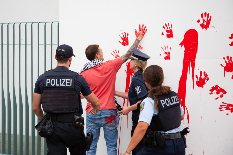 Am 07.07.2025 um 12 Uhr beschmierten Aktivist*innen von Palestine Rising die rechte Seite der Fassade des Bundeskanzleramtes in Berlin, Deutschland. Sie hinterließen rote Handabdrücke an der Wand. Sie demonstrieren damit gegen die deutsche Unterstützung von Kriegsverbrechen in Gaza.   --    On July 7, 2025 activists from Palestine Rising, a group of the New Generation, smeared the facade of the federal chancellery in Berlin, Germany with red paint. They left red hand prints at the wall. With their action the activists protest against German support for the Israeli war crimes in Gaza.