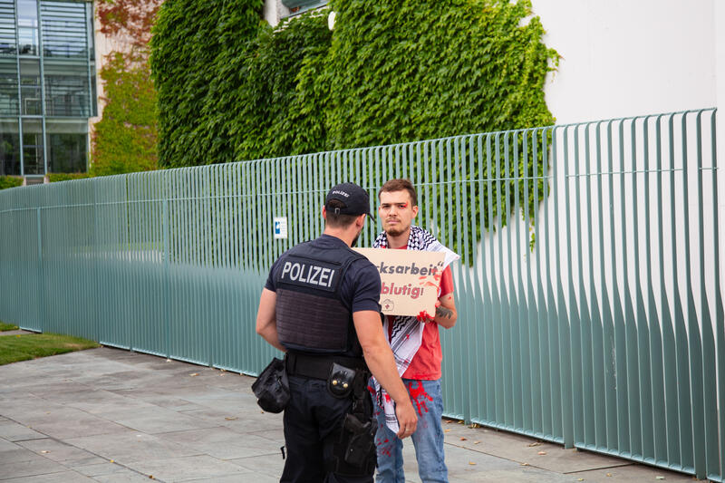 Am 07.07.2025 um 12 Uhr beschmierten Aktivist*innen von Palestine Rising die rechte Seite der Fassade des Bundeskanzleramtes in Berlin, Deutschland. Sie hinterließen rote Handabdrücke an der Wand. Sie demonstrieren damit gegen die deutsche Unterstützung von Kriegsverbrechen in Gaza.   --    On July 7, 2025 activists from Palestine Rising, a group of the New Generation, smeared the facade of the federal chancellery in Berlin, Germany with red paint. They left red hand prints at the wall. With their action the activists protest against German support for the Israeli war crimes in Gaza.