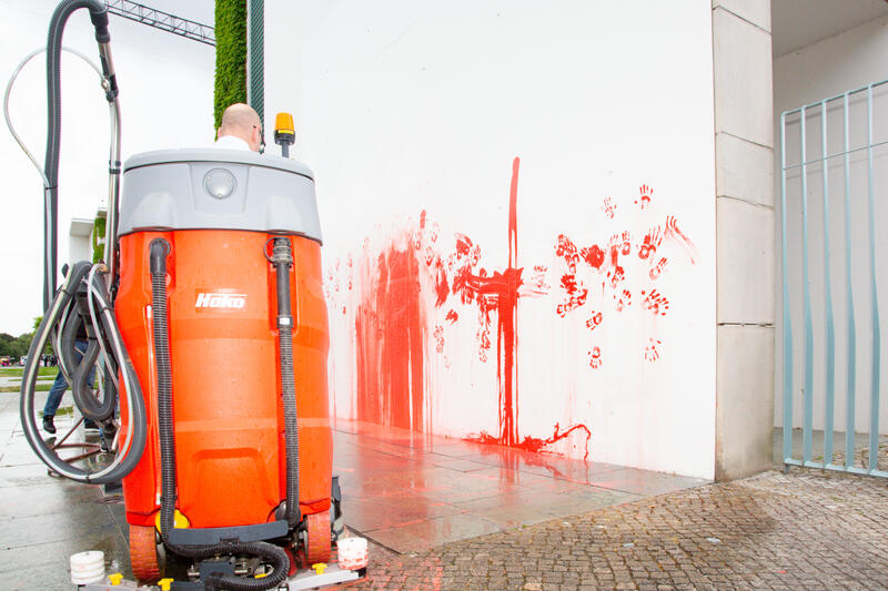 Reinigungsteam säubern die Stelle. Am 07.07.2025 um 12 Uhr beschmierten Aktivist*innen von Palestine Rising die rechte Seite der Fassade des Bundeskanzleramtes in Berlin, Deutschland. Sie hinterließen rote Handabdrücke an der Wand. Sie demonstrieren damit gegen die deutsche Unterstützung von Kriegsverbrechen in Gaza.   --    Cleaning team cleans the wall after the action. On July 7, 2025 activists from Palestine Rising, a group of the New Generation, smeared the facade of the federal chancellery in Berlin, Germany with red paint. They left red hand prints at the wall. With their action the activists protest against German support for the Israeli war crimes in Gaza.