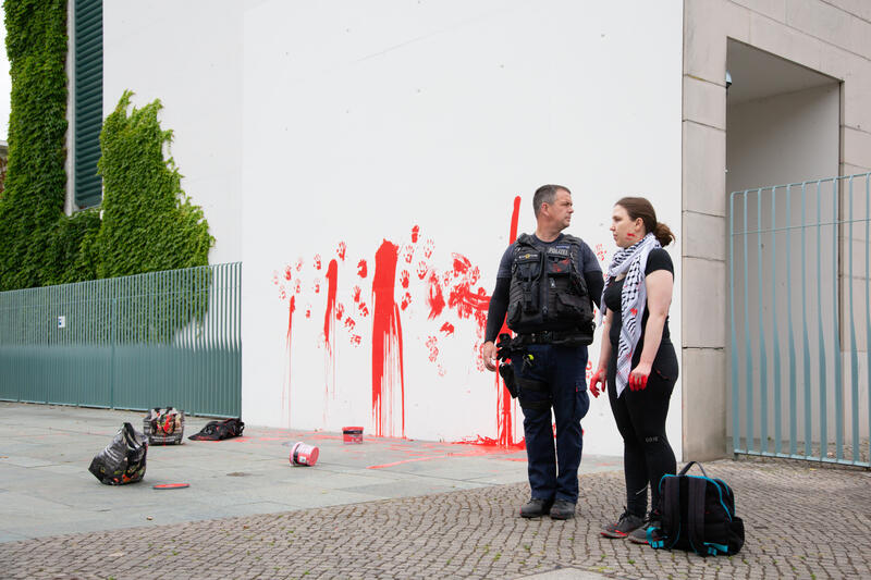 Am 07.07.2025 um 12 Uhr beschmierten Aktivist*innen von Palestine Rising die rechte Seite der Fassade des Bundeskanzleramtes in Berlin, Deutschland. Sie hinterließen rote Handabdrücke an der Wand. Sie demonstrieren damit gegen die deutsche Unterstützung von Kriegsverbrechen in Gaza.   --    On July 7, 2025 activists from Palestine Rising, a group of the New Generation, smeared the facade of the federal chancellery in Berlin, Germany with red paint. They left red hand prints at the wall. With their action the activists protest against German support for the Israeli war crimes in Gaza.