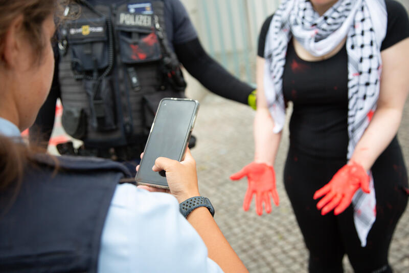 Am 07.07.2025 um 12 Uhr beschmierten Aktivist*innen von Palestine Rising die rechte Seite der Fassade des Bundeskanzleramtes in Berlin, Deutschland. Sie hinterließen rote Handabdrücke an der Wand. Sie demonstrieren damit gegen die deutsche Unterstützung von Kriegsverbrechen in Gaza.   --    On July 7, 2025 activists from Palestine Rising, a group of the New Generation, smeared the facade of the federal chancellery in Berlin, Germany with red paint. They left red hand prints at the wall. With their action the activists protest against German support for the Israeli war crimes in Gaza.