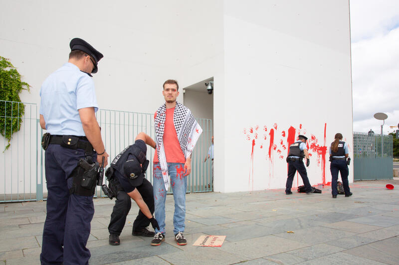 Am 07.07.2025 um 12 Uhr beschmierten Aktivist*innen von Palestine Rising die rechte Seite der Fassade des Bundeskanzleramtes in Berlin, Deutschland. Sie hinterließen rote Handabdrücke an der Wand. Sie demonstrieren damit gegen die deutsche Unterstützung von Kriegsverbrechen in Gaza.   --    On July 7, 2025 activists from Palestine Rising, a group of the New Generation, smeared the facade of the federal chancellery in Berlin, Germany with red paint. They left red hand prints at the wall. With their action the activists protest against German support for the Israeli war crimes in Gaza.