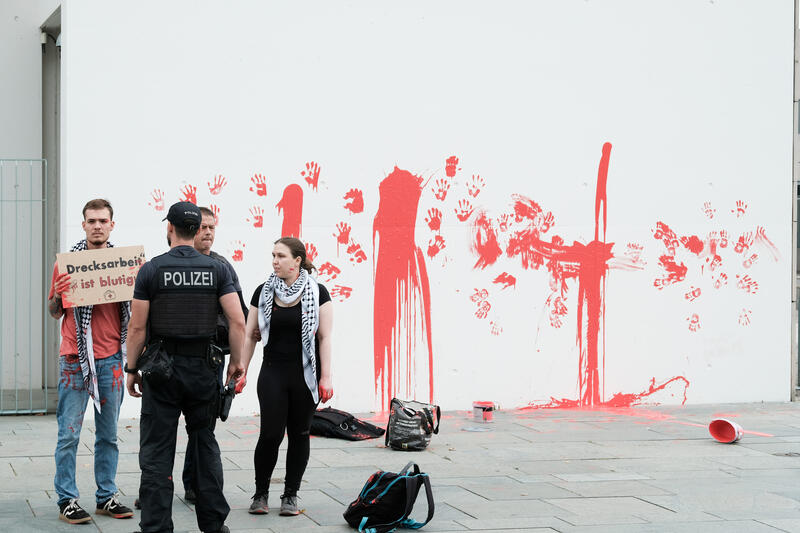 Am 07.07.2025 um 12 Uhr beschmierten Aktivist*innen von Palestine Rising die rechte Seite der Fassade des Bundeskanzleramtes in Berlin, Deutschland. Sie hinterließen rote Handabdrücke an der Wand. Sie demonstrieren damit gegen die deutsche Unterstützung von Kriegsverbrechen in Gaza.   --    On July 7, 2025 activists from Palestine Rising, a group of the New Generation, smeared the facade of the federal chancellery in Berlin, Germany with red paint. They left red hand prints at the wall. With their action the activists protest against German support for the Israeli war crimes in Gaza.