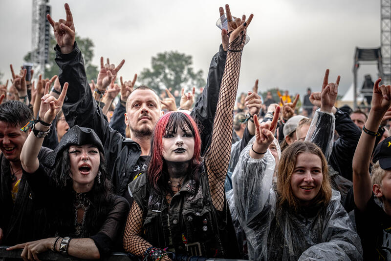 Am 2. August 2025 feiert das Publikum auf dem Wacken Open Air ausgelassen bei Regen, Matsch und lauter Musik. Ausdrucksstarke Gesichter, jubelnde Fans und bewegte Szenen spiegeln die einzigartige Festivalstimmung wider.
On August 2, 2025, the Wacken Open Air crowd celebrates in high spirits despite rain, mud, and loud music. Expressive faces, cheering fans, and dynamic scenes reflect the festival’s unmistakable atmosphere.