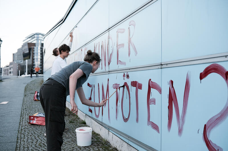 Am 02.09.2025 gegen 19 Uhr bemalten drei junge Aktivist*innen die Wand vom Kindergarten des Bundestags mit den Worten " Verpflichtet ihr auch eure Kinder zum Töten? " mit Kunstblut, um gegen eine mögliche Wehrpflicht zu demonstrieren. Auf Schildern stand zusätzlich " Wir verweigern ".   --   On September 2, 2025 three young activists wrote " Do you also draft your children to kill? " on the wall of the kindergarden of the Bundestag with artificial blood to protest against the planned reintroduction of the conscription. On signs there was written " We object ".