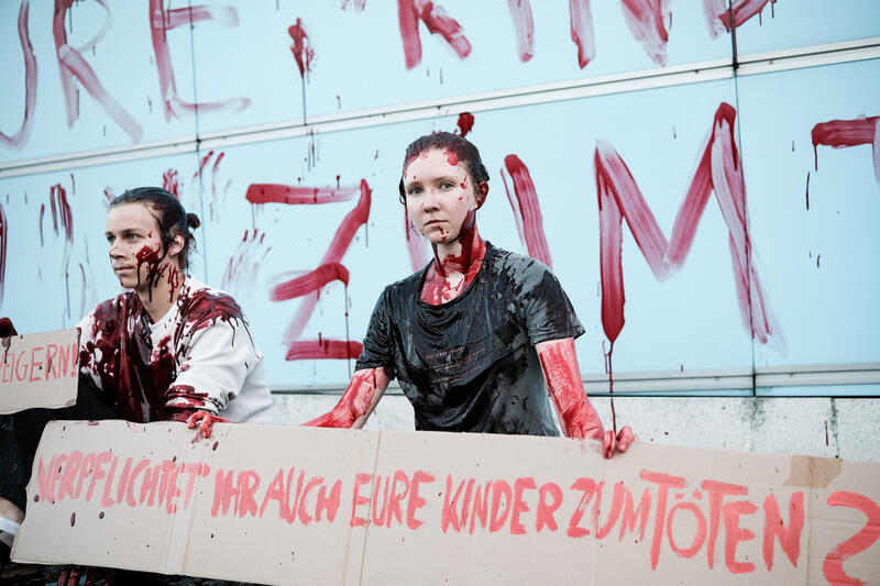 Am 02.09.2025 gegen 19 Uhr bemalten drei junge Aktivist*innen die Wand vom Kindergarten des Bundestags mit den Worten " Verpflichtet ihr auch eure Kinder zum Töten? " mit Kunstblut, um gegen eine mögliche Wehrpflicht zu demonstrieren. Auf Schildern stand zusätzlich " Wir verweigern ".   --   On September 2, 2025 three young activists wrote " Do you also draft your children to kill? " on the wall of the kindergarden of the Bundestag with artificial blood to protest against the planned reintroduction of the conscription. On signs there was written " We object ".