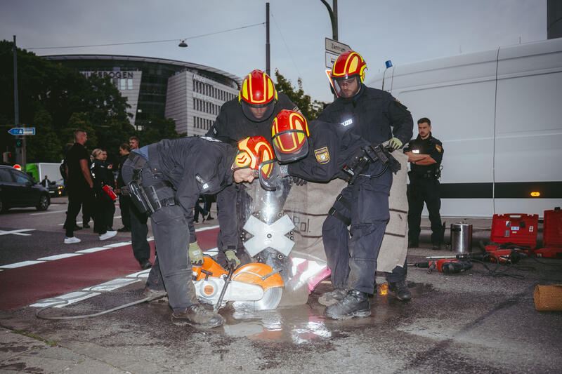 Am Morgen des 9. September 2025 blockierten Aktivist*innen des Widerstandskollektivs die Landshuter Allee in München, Deutschland, vor dem Mercedes Showroom, um gegen die IAA (Internationale Automobil-Ausstellung) zu protestieren.
Einige saßen dabei nur auf der Straße, andere klebten oder betonierten sich fest. Die festbetonierte Aktivist*in musste mit Hilfe einer Flex gelöst werden. --   On the morning of September 9, 2025, activists from the Resistance Collective blocked Landshuter Allee in Munich, Germany, in front of the Mercedes showroom to protest against the IAA (International Motor Show).
Some just sat on the street, others stuck or concreted themselves down.
The concreted activist had to be loosened with the help of an angle grinder.