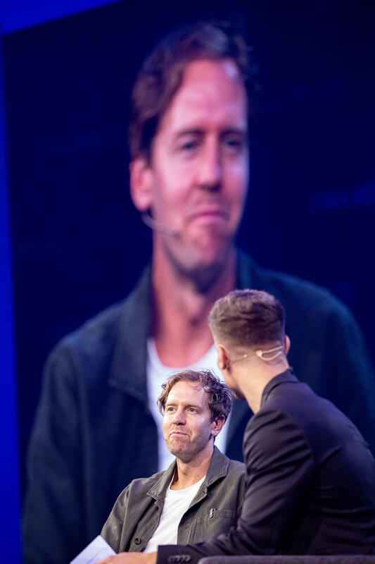 Sebastian Vettel, Simon Schütz, VDA Head of Communications,  bei der IAA Conference auf der IAA Mobility am 09.09.2025 in München.   --   Sebastian Vettel, Simon Schuetz, VDA Head of Communications, at the IAA Conference at the IAA Mobility on September 9, 2025 in Munich, Germany.