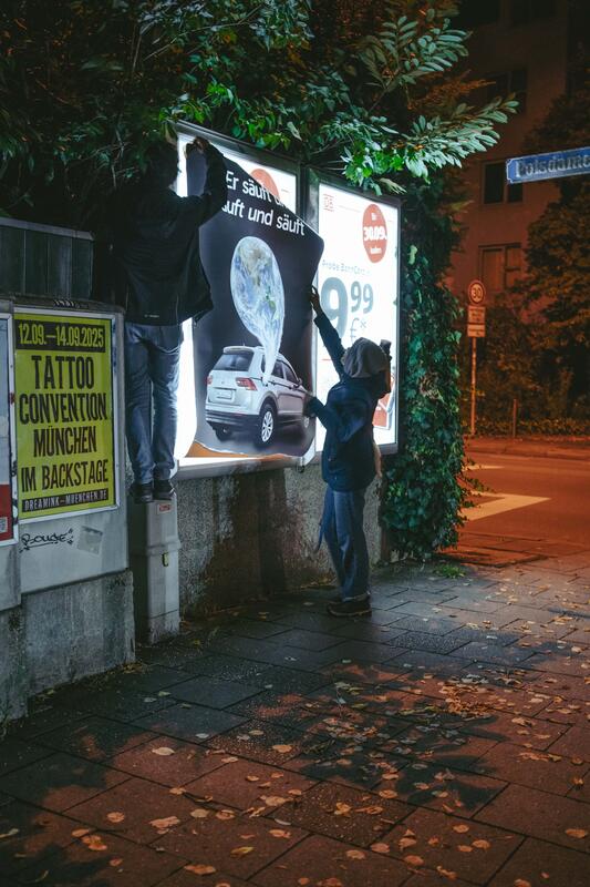 In der Nacht auf den 10.09.2025 versuchten zwei Aktivist:innen von Attac eine Adbusting-Aktion. Sie entfernten einige Werbeplakate und wollten sie durch Plakate gegen die IAA ersetzen. Da sie unvorbereitet waren, konnten sie einige Werbekästen nicht öffnen, einige konnten sie hingegen öffnen, aber ihre Plakate nicht aufhängen. Der Protest von Attac gegen die IAA begleiten sie mit der Froderung, nach einer sozial-ökologischen Wende in der Automobilindustrie und im gesamten Wirtschaftssystem. Sie fordern: Weniger Autos, und stattdessen mehr Platz für Fahrräder und Fußwege. -- On the night of September 10, 2025, two Attac activists attempted an adbusting campaign. They removed several advertising posters and wanted to replace them with posters against the IAA. Since they were unprepared, they were unable to open some of the advertising boxes, while others they were able to open but could not hang their posters. Attac's protest against the IAA is accompanied by demands for a socio-ecological transformation of the automotive industry and the entire economic system. They are calling for fewer cars and more space for bicycles and footpaths instead.