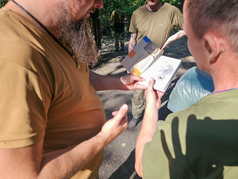 Anton Lubii schreibt einem Soldaten eine Widmung in ein Buch. Fotografiert am 7. September 2025.      Anton Lubii writes a dedication to a soldier in a book. Photographed on 7 September 2025.