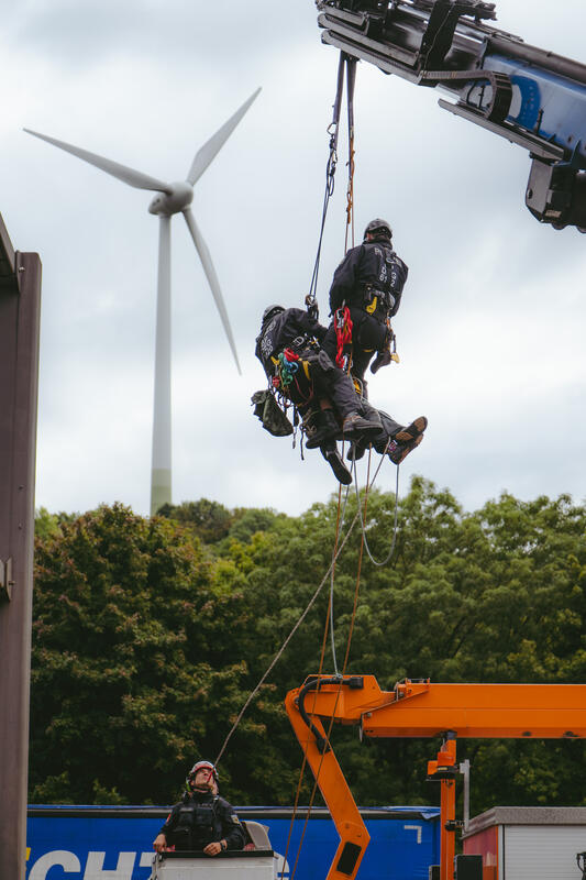Am 11. September 2025, kurz nach 8, steigen drei Aktivist*innen auf eine Schilderbrücke über der Autobahn nahe der Allianz-Arena in München, Deutschland.
Dazu setzen sich wenig später 6 weitere Aktivist*innen auf die mittlerweile gesperrte Autobahn und kleben sich teilweise fest.
Auch zwei der Aktivist*innen auf der Brücke klebten sich fest, dies verzögerte die Räumung um einiges. Die Aktivist*innen gehörten dem Widerstandskollektiv an und protestierten mit dieser Aktion gegen die IAA, die zurzeit in München stattfindet.  -- On September 11, 2025, shortly after 8 a.m., three activists climb onto a sign bridge above the highway near the Allianz Arena in Munich, Germany.
A little later, six more activists sit down on the now closed highway and partially glue themselves to the ground.
Two of the activists on the bridge also glued themselves to the bridge, which delayed the evacuation considerably. The activists belonged to the resistance collective and were protesting against the IAA, which is currently taking place in Munich.