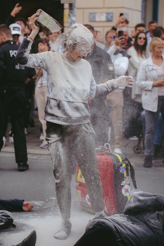 Am 11. September 2025 beteiligten sich um die zwei Dutzend Aktivist*innen an einer Die-In-Aktion von Extinction Rebellion gegen die IAA in München, Deutschland. Dabei legte sich der Großteil auf die Straße und spielte tot. Drei der Aktivist*innen begossen sich mit Mehl, Cola und einem roten Saft, um Staub, Öl und Blut darzustellen. -- On September 11, 2025, around two dozen activists took part in a die-in protest organized by Extinction Rebellion against the IAA in Munich, Germany. Most of them lay down on the street and pretended to be dead. Three of the activists covered themselves in flour, cola, and red juice to represent dust, oil, and blood.