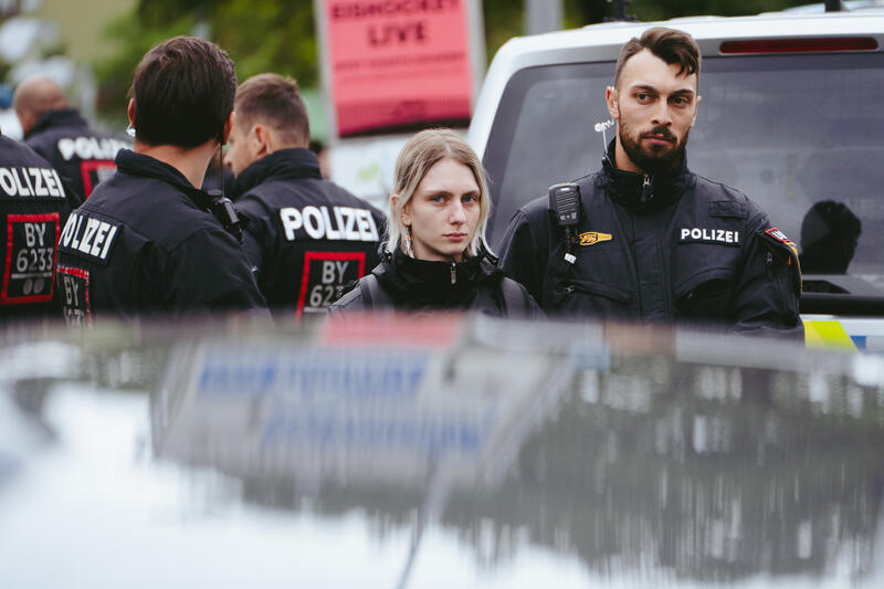 Am 12. September 2025 versammelten sich um die 50 Teilnehmer*innen zu einem Straßenfest gegen die IAA auf einem Grünstreifen vor der BMW-Welt in München, Deutschland. Während der Versammlung kam es immer wieder zu ungehorsamen Aktionen wie dem Besetzen der Straße und dem Klettern auf ein Polizeiauto.  -- On September 12, 2025, around 50 participants gathered for a street party against the IAA on a grass verge in front of BMW Welt in Munich, Germany. During the gathering, there were repeated acts of civil disobedience, such as occupying the street and climbing on a police car.