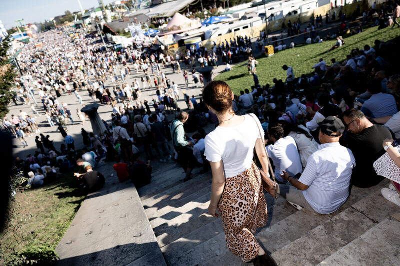 Besucher schauen von der Bavaria Treppe auf die Theresienwiese. Impressionen vom Oktoberfest am ersten Wiesnsonntag am 21.09.2025 in München.   --  Visitors look down from the Bavaria chairs to the Theresienwiese. Impression from the Oktoberfest on the first sunday on September 21, 2025 in Munich, Germany.