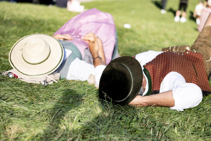 Besucher schlafen / entspannen am Kotzhügel. Impressionen vom Oktoberfest am ersten Wiesnsonntag am 21.09.2025 in München.   --   Visitors sleep / relax at the so called vomit hill. Impression from the Oktoberfest on the first sunday on September 21, 2025 in Munich, Germany.