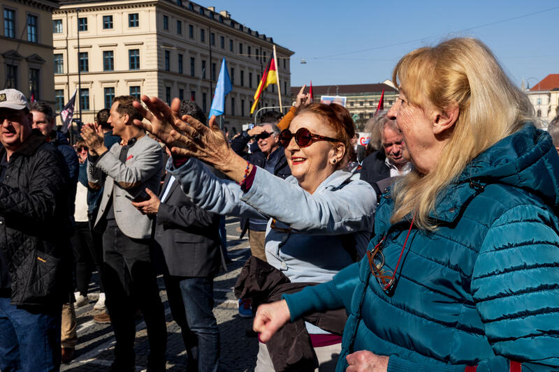 AfD Publikum jubelt bei der Kundgebung der AfD Bayern zur Kommunalwahl am 07.03.2026 am Odeonsplatz in München. Drum herum versammelten sich zahlreiche Gegendemonstrant:innen.   --   AfD audience cheers at the election campaign rally of the AfD for the municipal elections on March 07, 2026 in Munich, Germany. Several counter-protestors encircled the rally space.