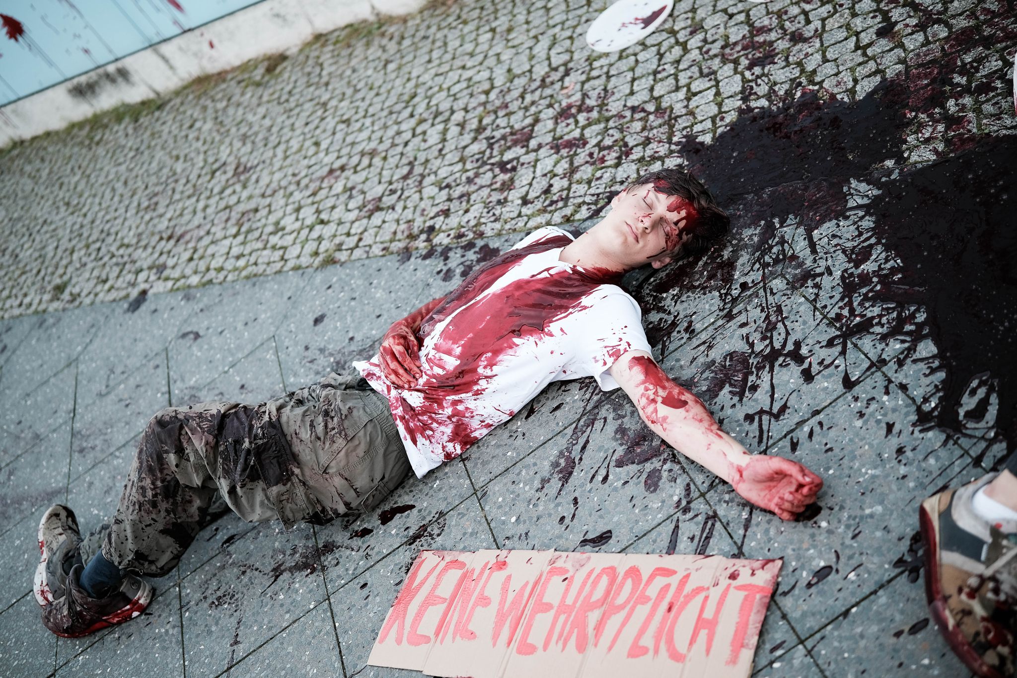 Am 02.09.2025 gegen 19 Uhr bemalten drei junge Aktivist*innen die Wand vom Kindergarten des Bundestags mit den Worten &quot; Verpflichtet ihr auch eure Kinder zum Töten? &quot; mit Kunstblut, um gegen eine mögliche Wehrpflicht zu demonstrieren. Auf Schildern stand zusätzlich &quot; Wir verweigern &quot;.   --   On September 2, 2025 three young activists wrote &quot; Do you also draft your children to kill? &quot; on the wall of the kindergarden of the Bundestag with artificial blood to protest against the planned reintroduction of the c