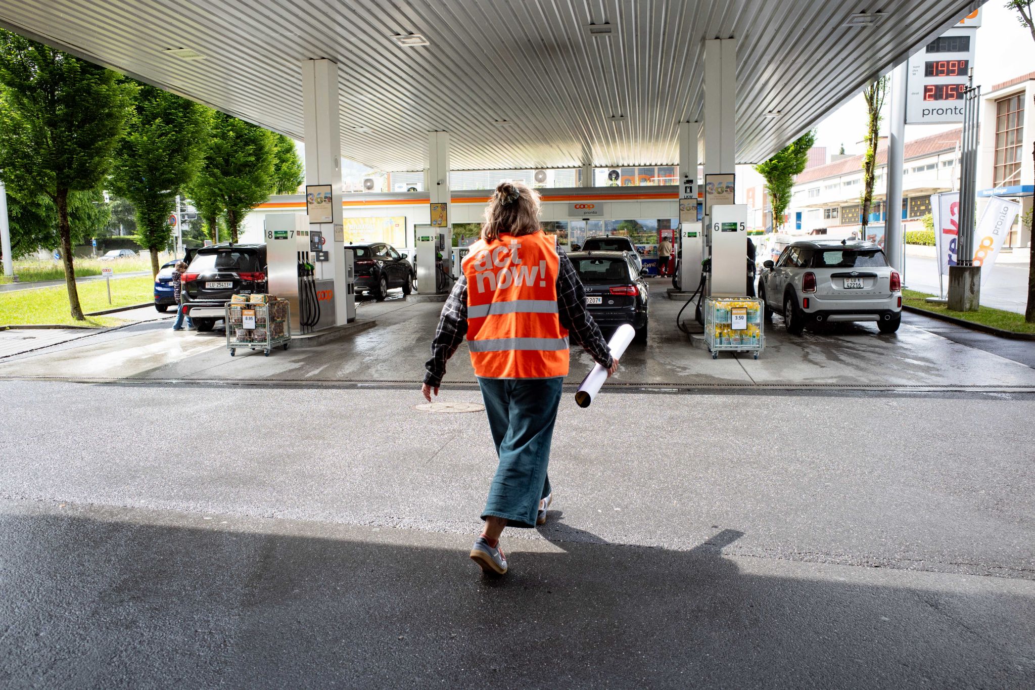 Eine Aktivistin von Act Now geht auf die Coop Pronto Tankstelle zu.